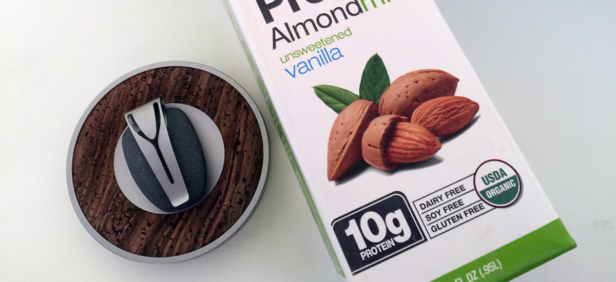 Vanilla protein almond milk next to a kitchen scale. Packaging highlights 10g protein, dairy-free, soy-free, gluten-free, and organic.