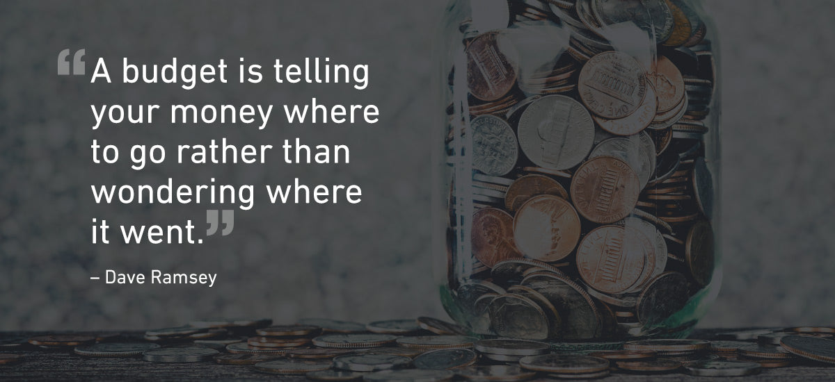 A glass jar filled with various coins is placed on a wooden surface. Beside it, the quote, "A budget is telling your money where to go rather than wondering where it went." is displayed, attributed to Dave Ramsey. The background is blurred.