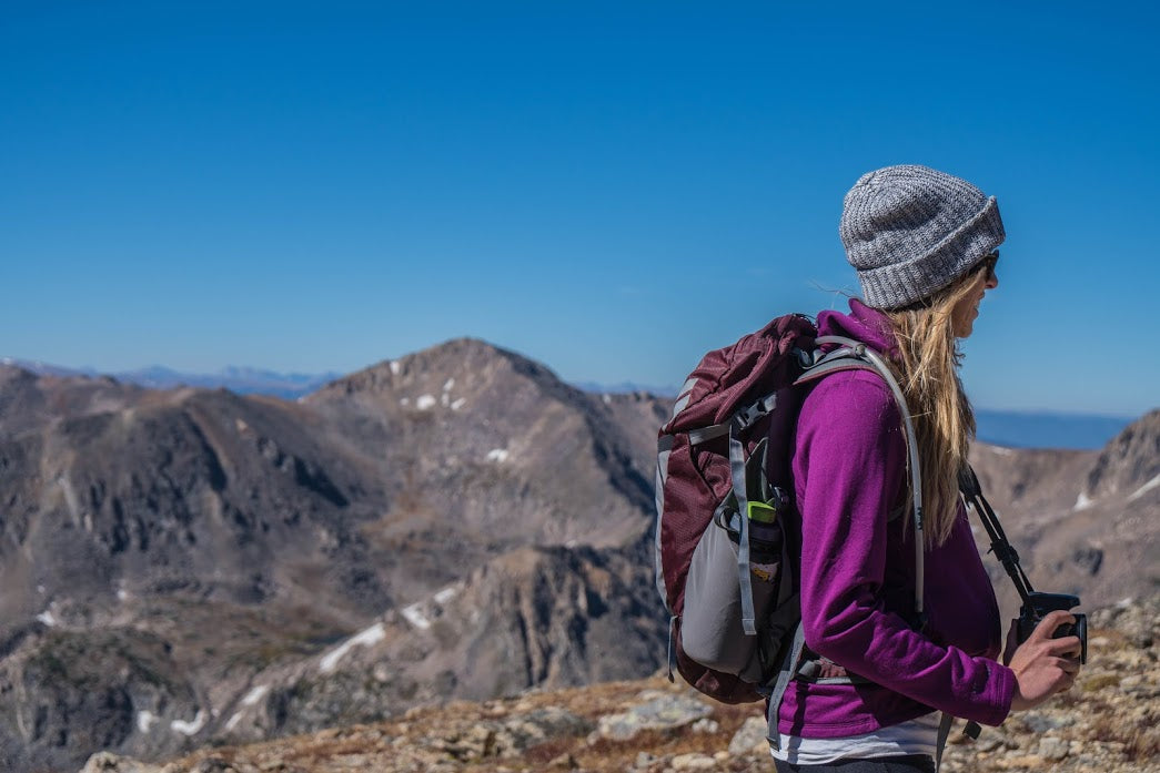A blonde-haired woman hiking through the mountains alone.