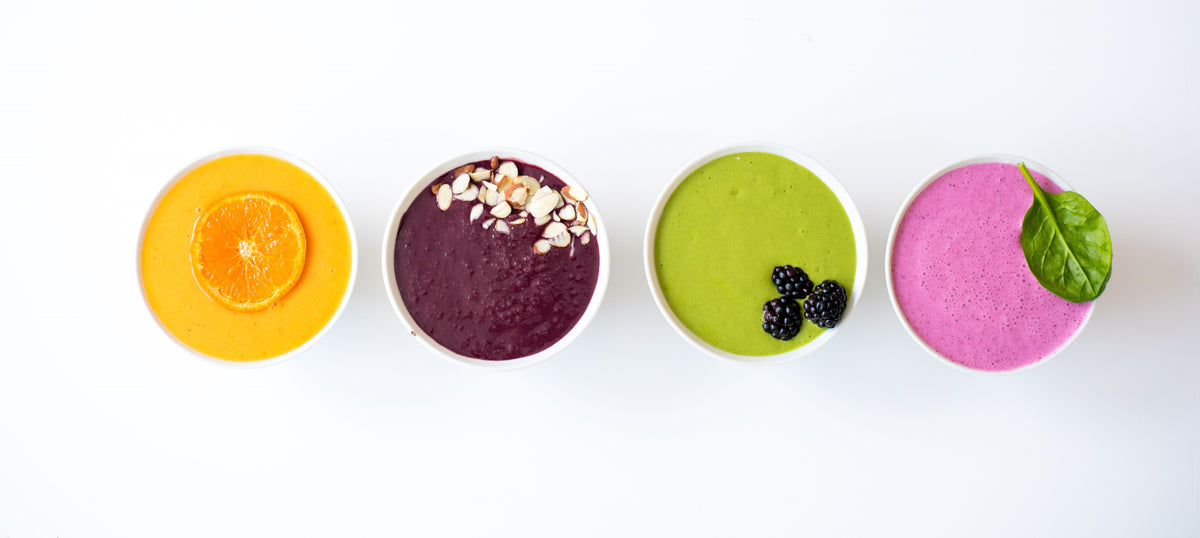 four different smoothies sitting on a kitchen counter.