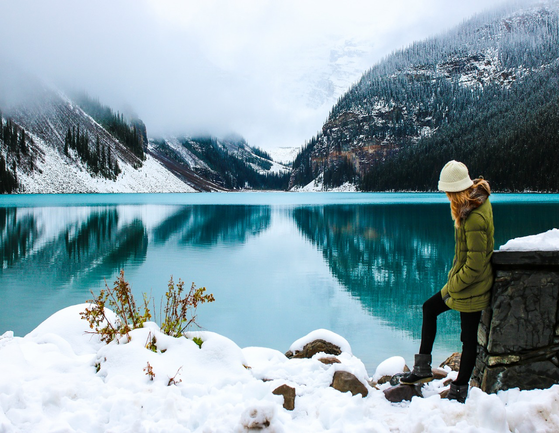 A woman stands beside a wintry lake in Alaska.