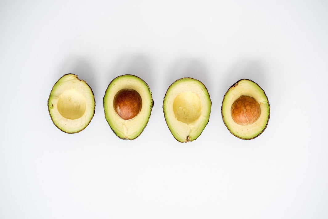 Two avocados sliced in half on the counter.