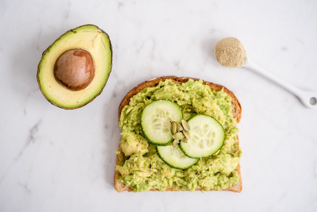A slice of avocado toast and two ingredients on the counter.
