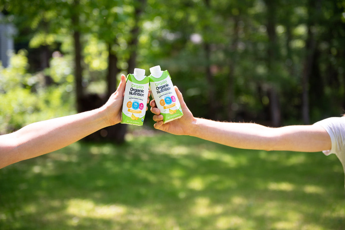 Two women cheersing their Organic Nutrition shakes by Orgain outside