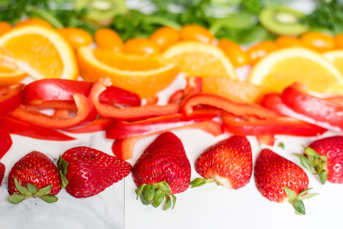 oranges and bell peppers and strawberries sliced on a table