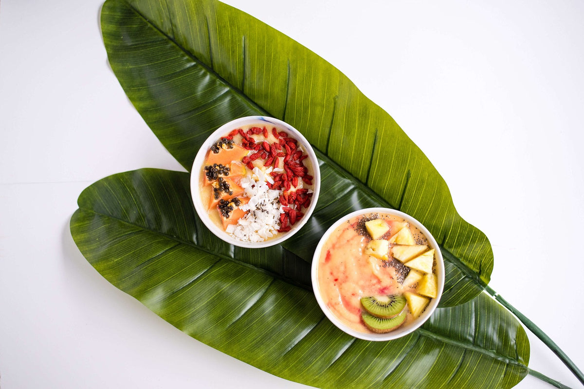 two smoothies on top of large green leaves