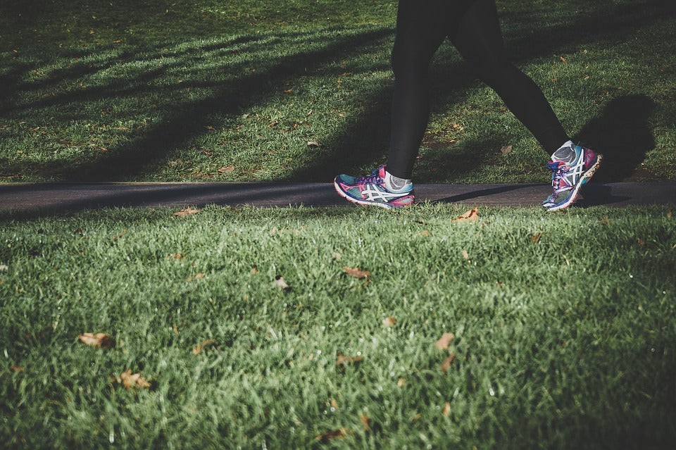 Ground-level side view of a woman running through the park.