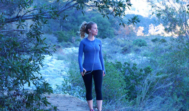 woman with a blue shirt walking on a hiking trail