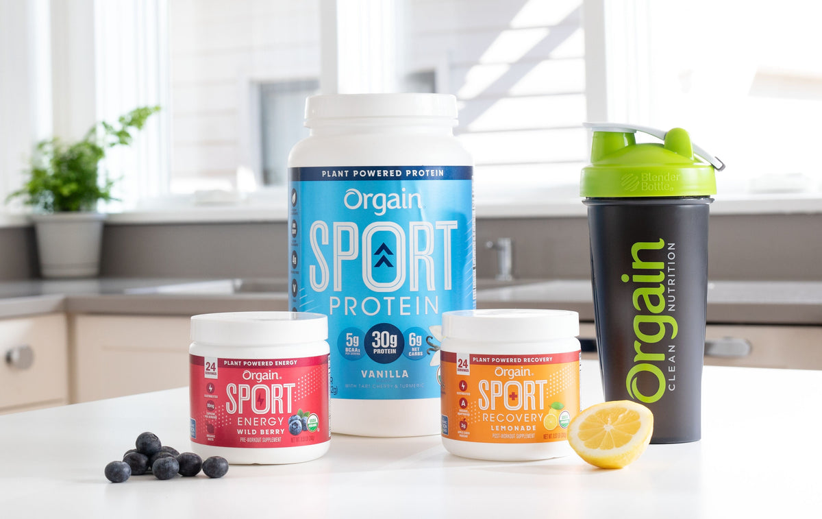 Orgain sport nutrition products on a kitchen counter, including energy, protein, and recovery containers.