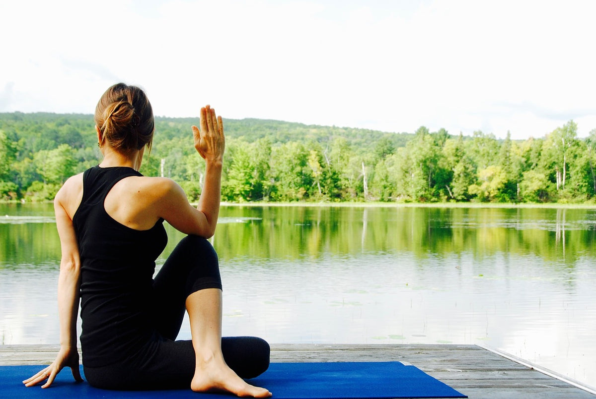A woman practicing yoga beside a lake