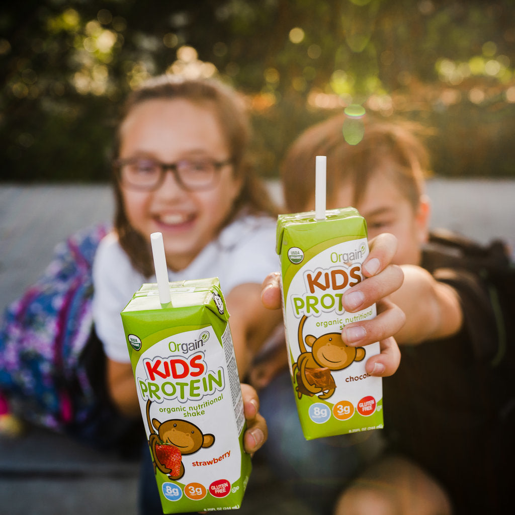 Two happy kids holding Kids' Protein shakes by Orgain